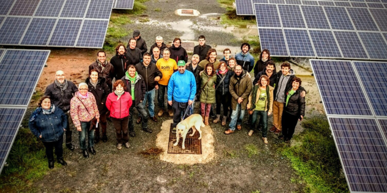 Socios de Som Energía posando junto a paneles fotovoltaicos.