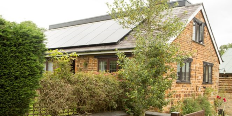 Vivienda unifamiliar con tejado a dos aguas y paneles fotovoltaicos sobre la cubierta.