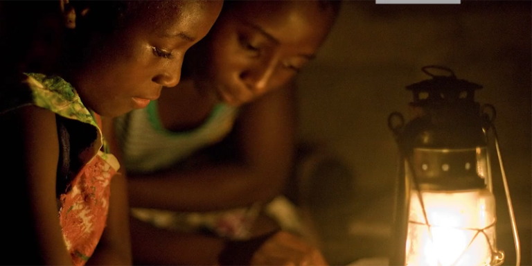 Dos niñas africanas estudian a la luz de un candil.