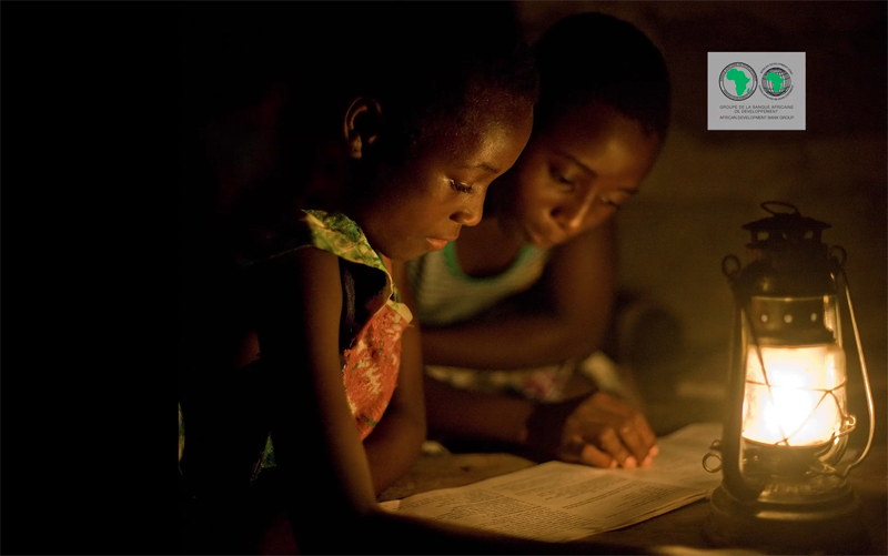 Dos niñas africanas estudian a la luz de un candil. 