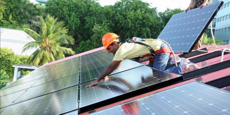 Profesional instalando placas solares sobre la cubierta de un edificio.