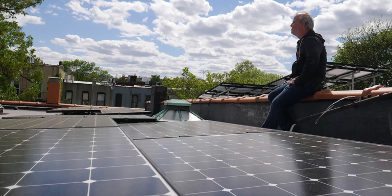 Miembro de Microgrid Brooklyn posando junto a paneles fotovoltaicos.