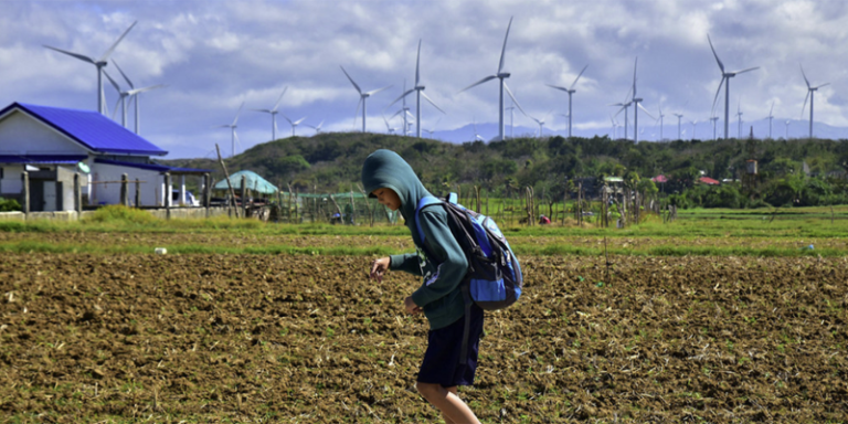 Un estudiante pasa frente a una granja de energía eólica en Filipinas